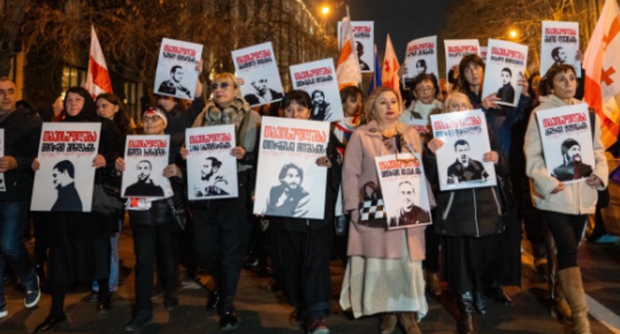 Участники марша в Тбилиси держат портреты и плакаты с требованием освободить политических заключённых