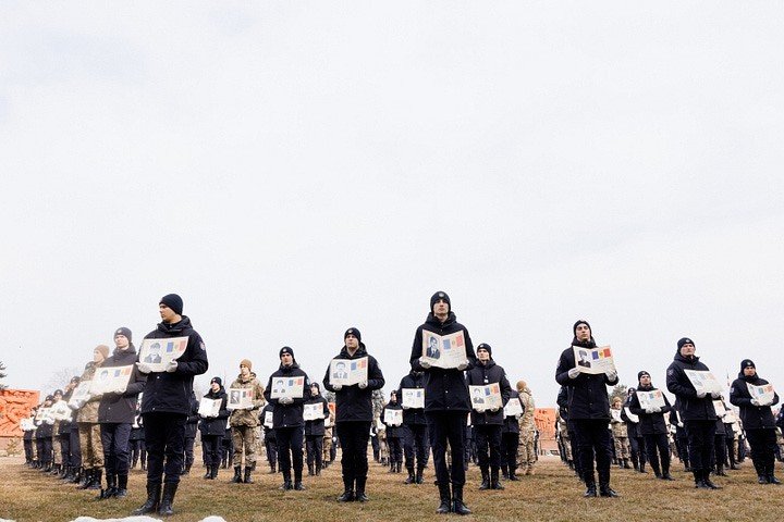 Молдавские военнослужащие держат портреты погибших героев на мемориальной церемонии