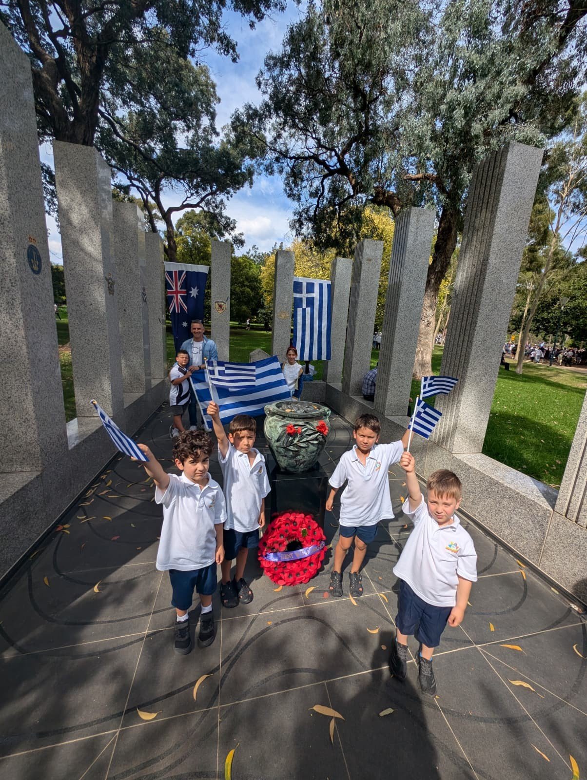 Дети с греческими флажками у мемориального памятника в Мельбурне