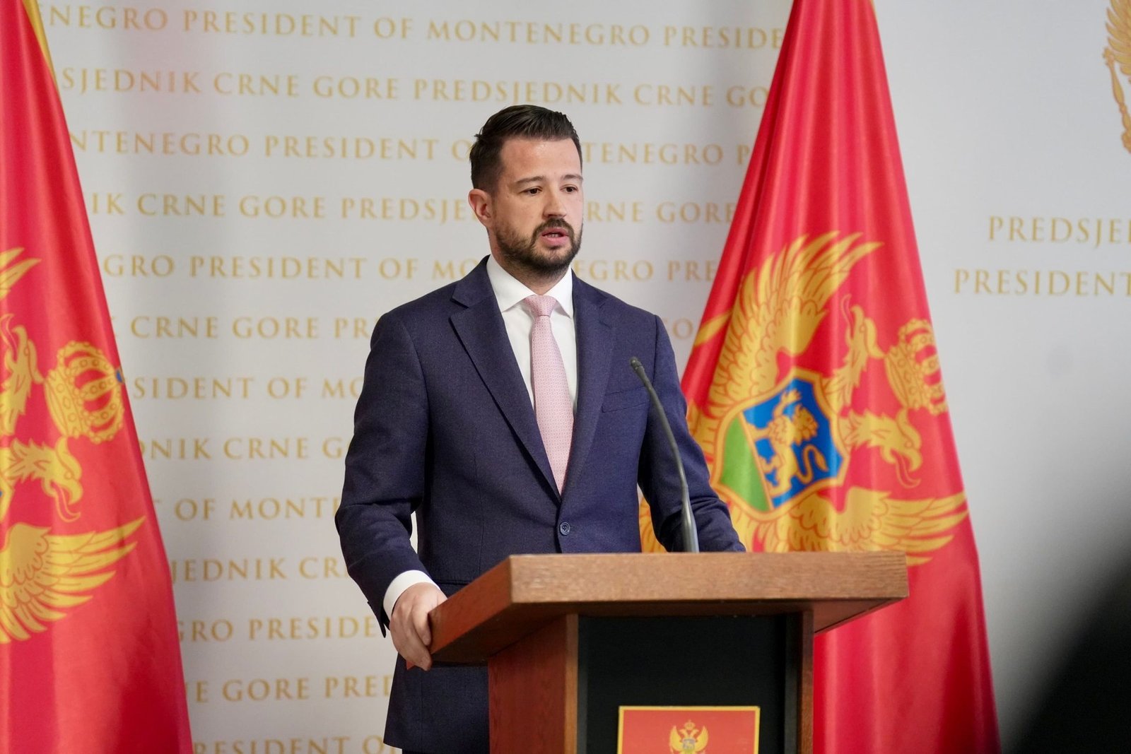 Президент Черногории Яков Милатович делает заявление на трибуне в резиденции президента на фоне государственных флагов