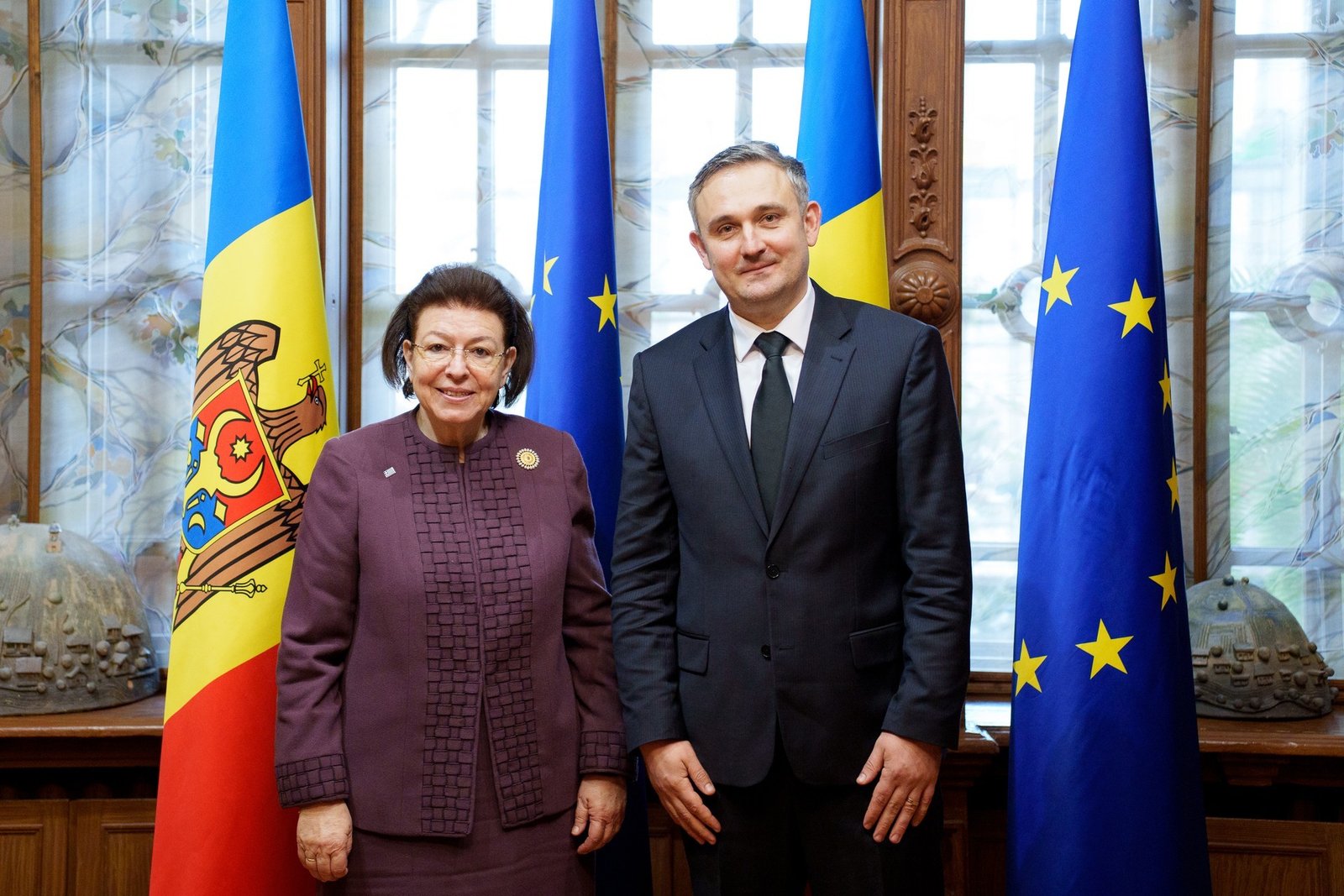Министр культуры Греции и министр культуры Молдовы позируют вместе на фоне молдавского и европейского флагов после подписания меморандума