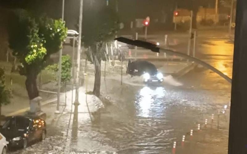 Автомобиль проезжает по затопленной улице ночью во время сильного ливня в Греции