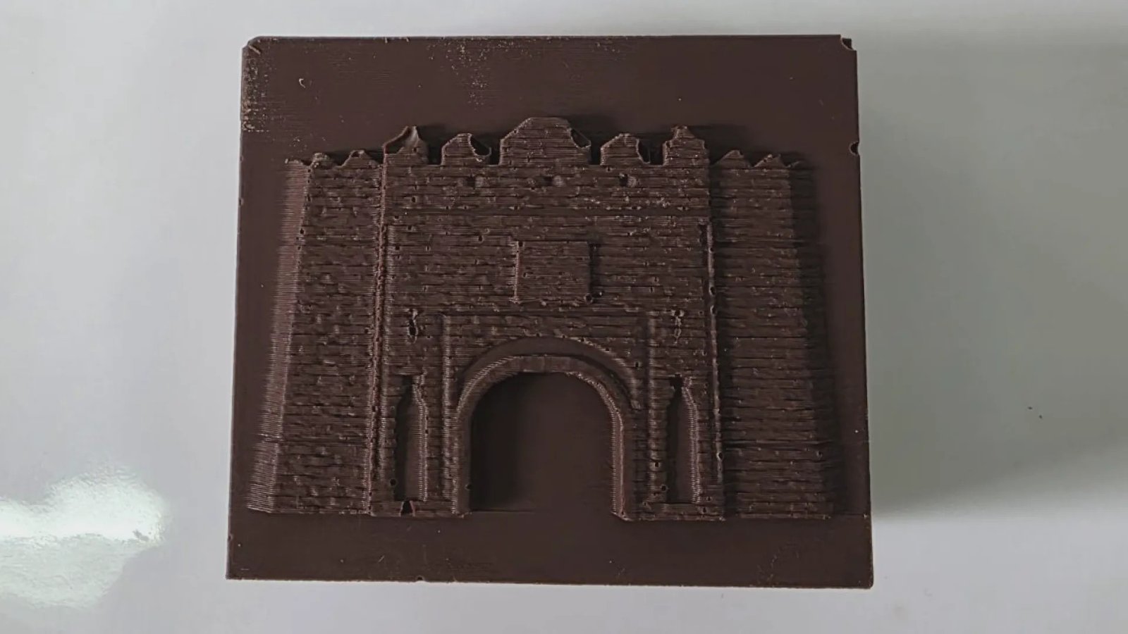 Детальный вид шоколадной крепости с проработанной текстурой кирпичной кладки и арочными воротами, изготовленной из безглютенового шоколада со шпинатом