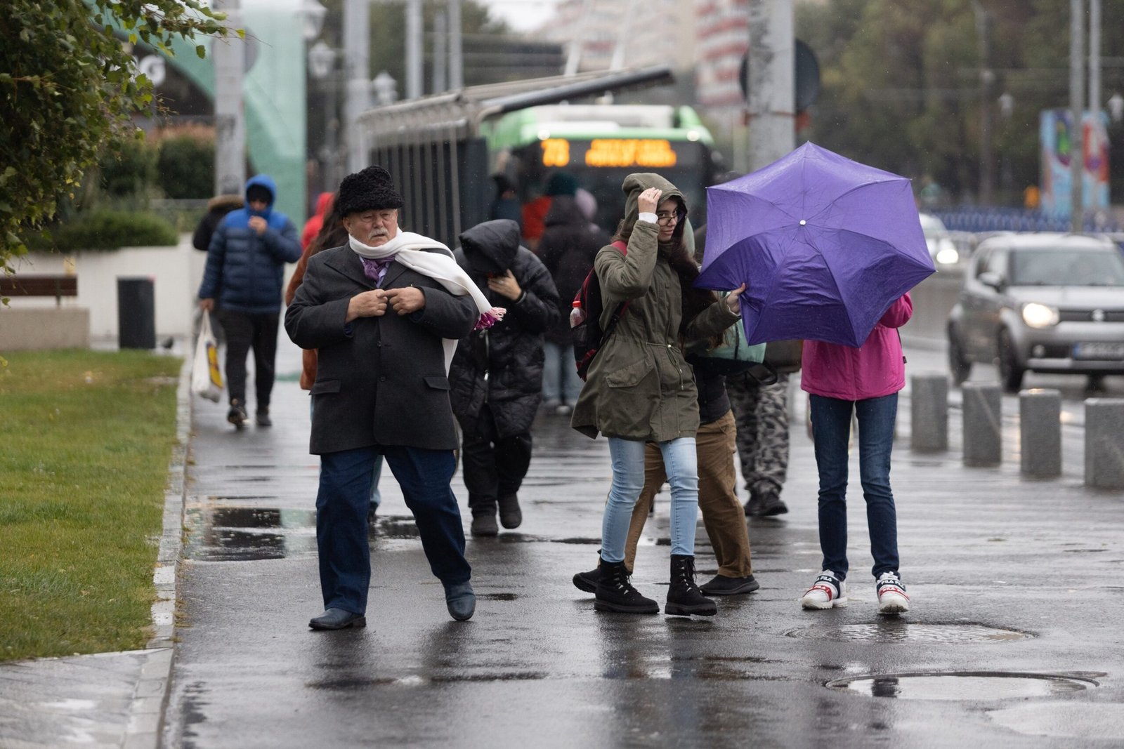 Пешеходы борются с ветром и дождём на городской улице