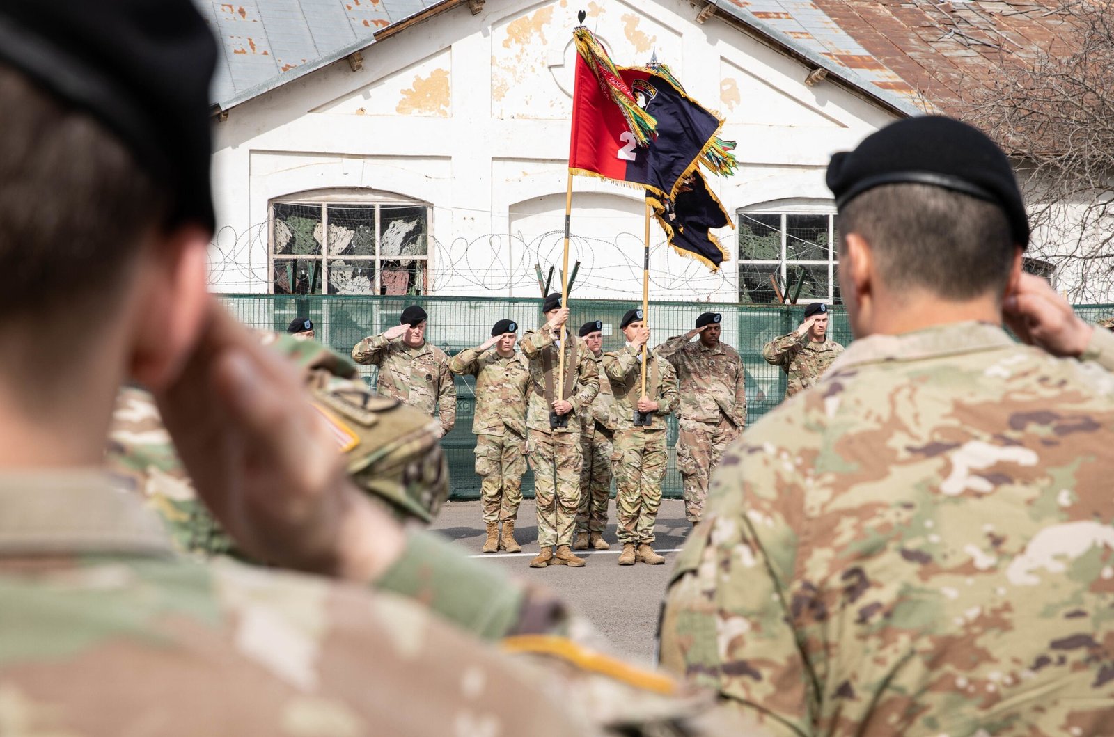 Военная церемония на базе в Румынии — солдаты отдают честь у знамени подразделения