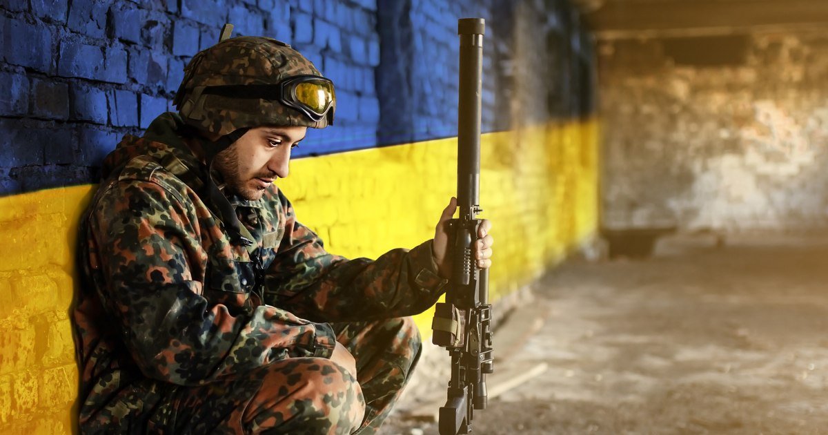 Украинский солдат на фоне стены в цветах украинского флага