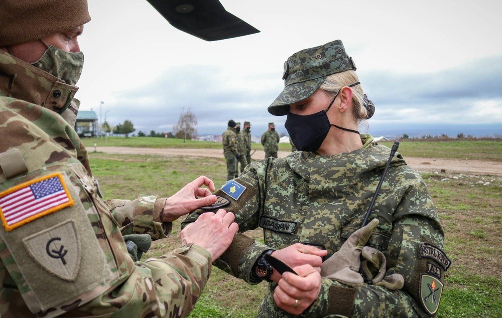 Американский военнослужащий обменивается нашивкой с военнослужащей Сил безопасности Косово во время совместных учений