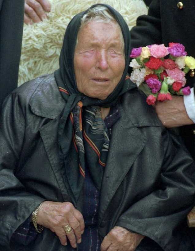 Historical photograph of Baba Vanga wearing a dark headscarf and coat, holding flowers. Фото: Global Disinformation Lab, UT Austin
