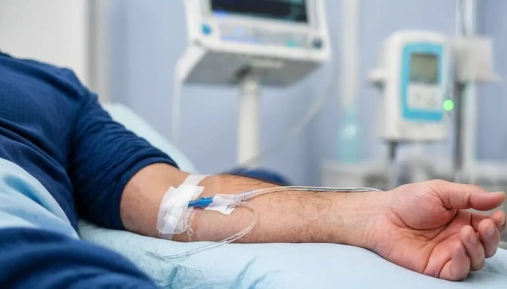 Рука пациента с внутривенным катетером на больничной койке рядом с инфузионным монитором — иллюстрация неоадъювантной иммунотерапии перед операцией