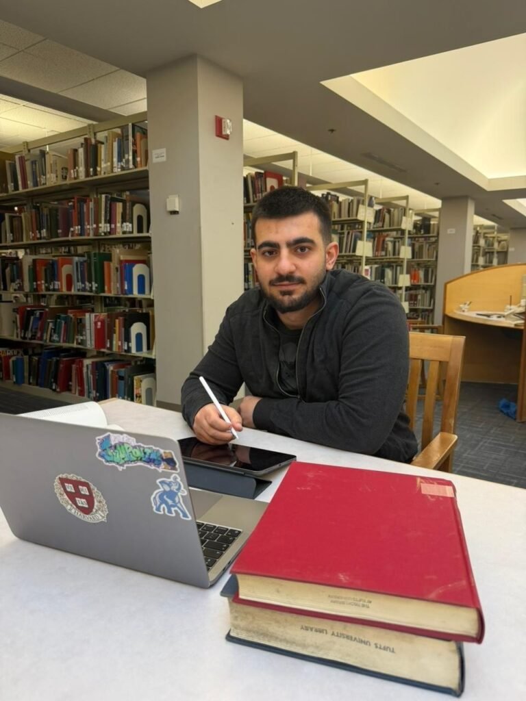 Студент из Азербайджана создал медицинскую платформу Care в США Молодой человек сидит за столом в библиотеке с ноутбуком и планшетом