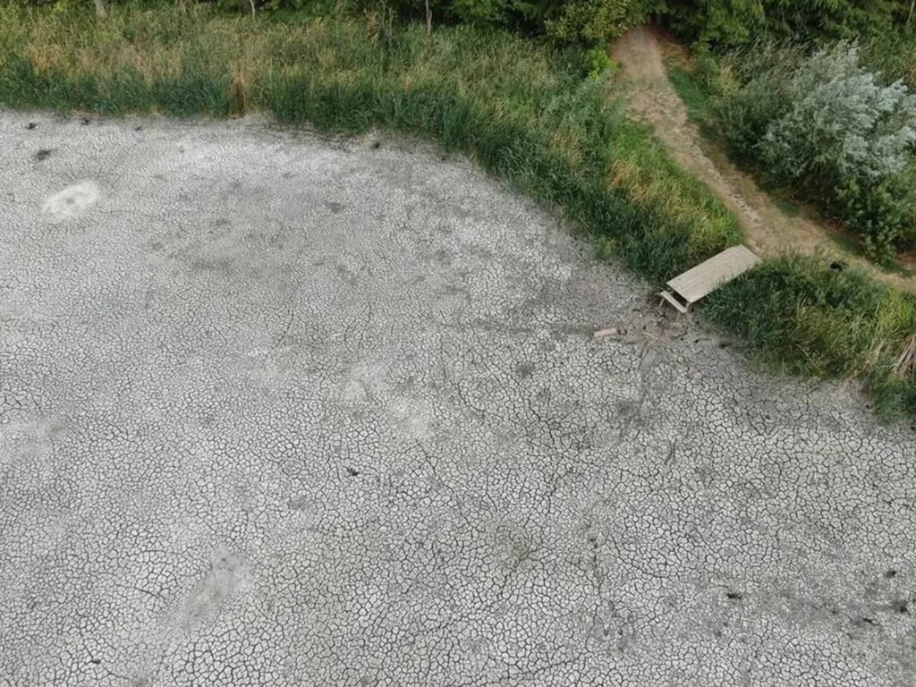 Почему мелеют озёра Румынии: засуха, наносы и цифры кризиса Высохшее озеро в Румынии — вид сверху на потрескавшееся дно водоёма с остатками деревянного причала