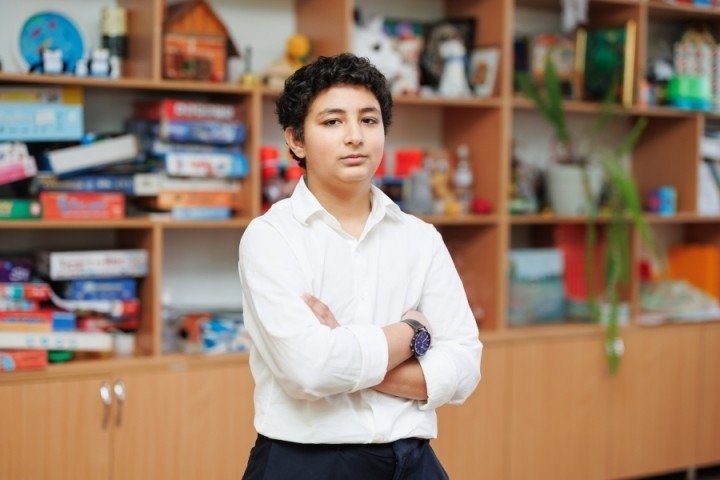 Михаил, ромский ученик из Сорок, уверенно стоит в классе со скрещёнными руками