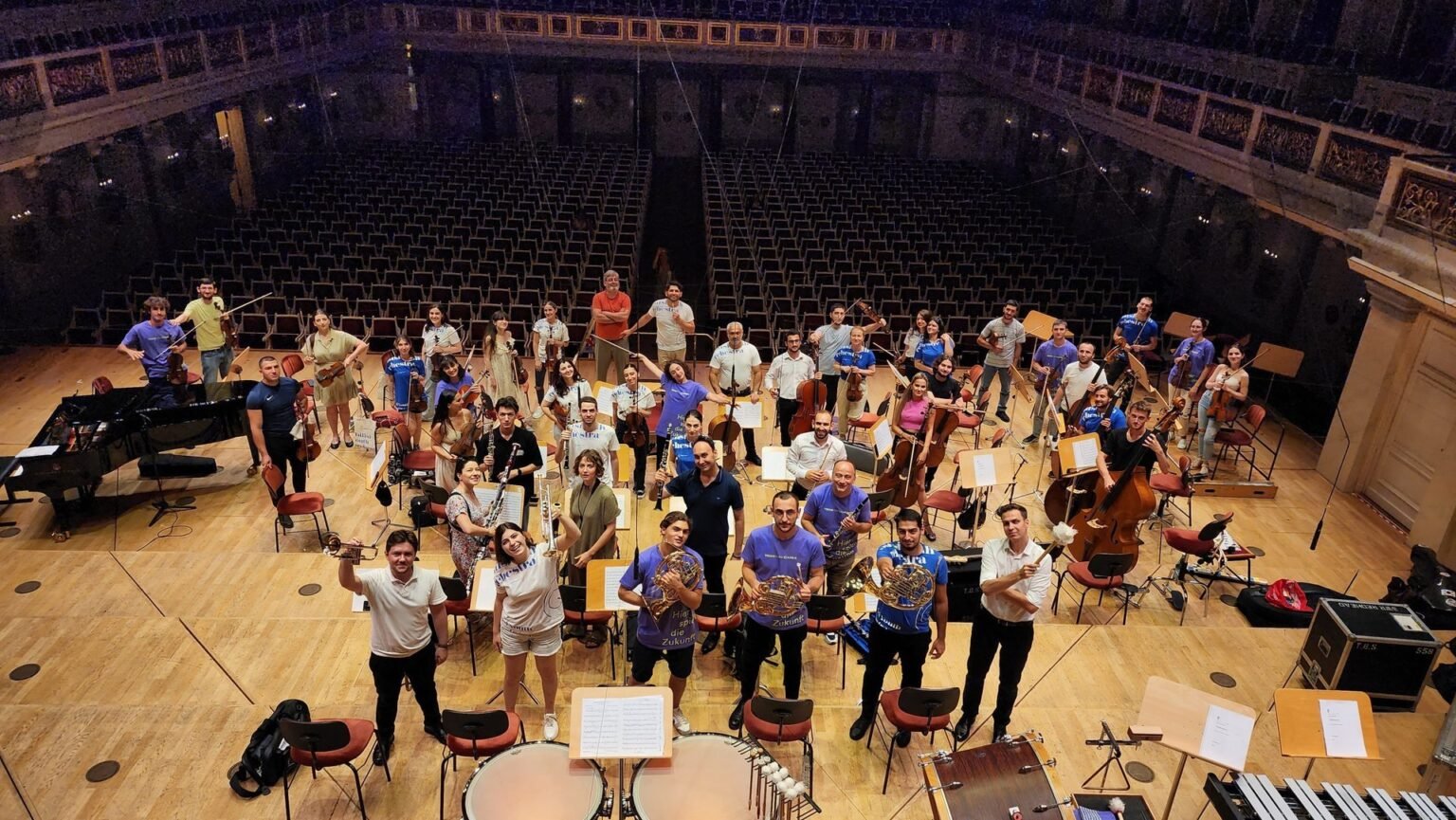 Молодёжный оркестр Тбилиси на сцене концертного зала — групповое фото музыкантов с инструментами