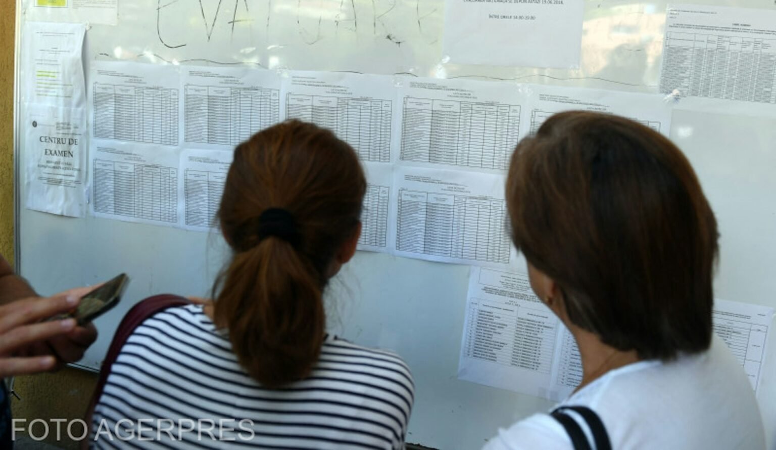 Симуляция бакалавриата в Румынии: результаты улучшились по всем предметам Выпускницы изучают списки результатов пробного экзамена на бакалавриат, вывешенные на стене экзаменационного центра