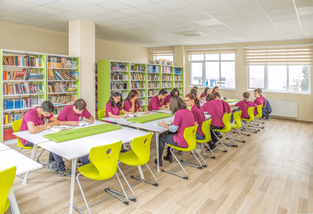 Сколько стоит частная школа в Румынии в 2026 году Ученики в розовой форме занимаются в школьной библиотеке частного учебного заведения в Румынии