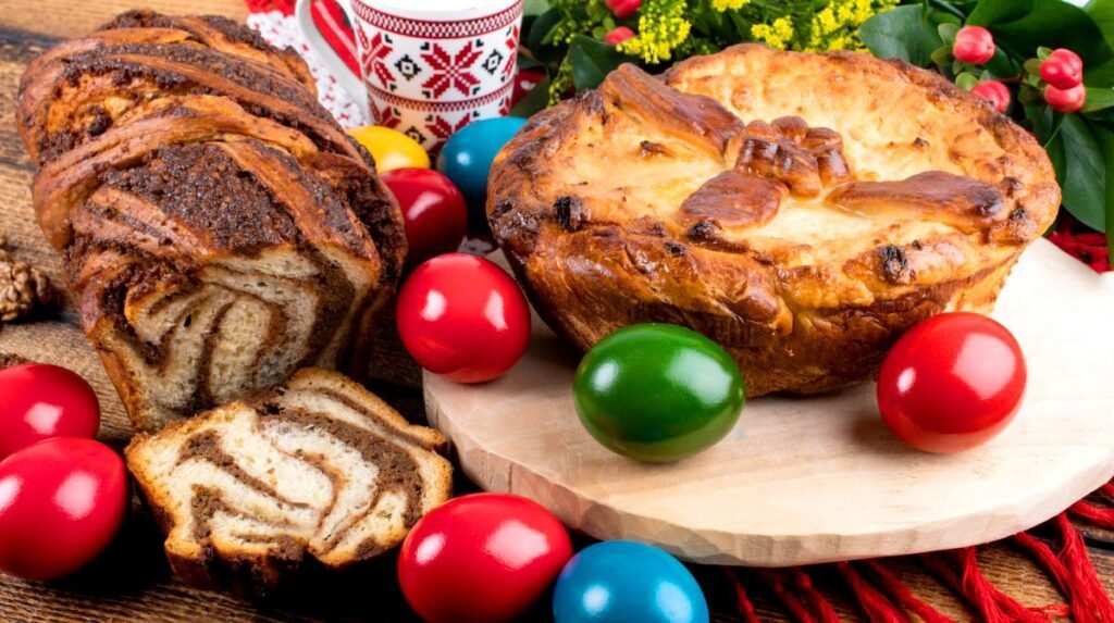 Пасха с крестом, козунак и крашеные яйца на праздничном столе Пасхи Блажинов