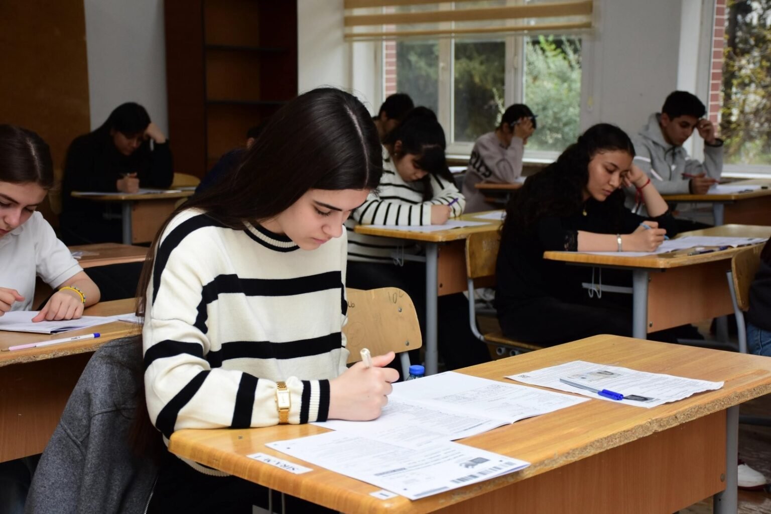 Выпускники азербайджанской школы сосредоточенно пишут бураxılış имтаhan в обычной классной комнате: на партах экзаменационные буклеты и ручки