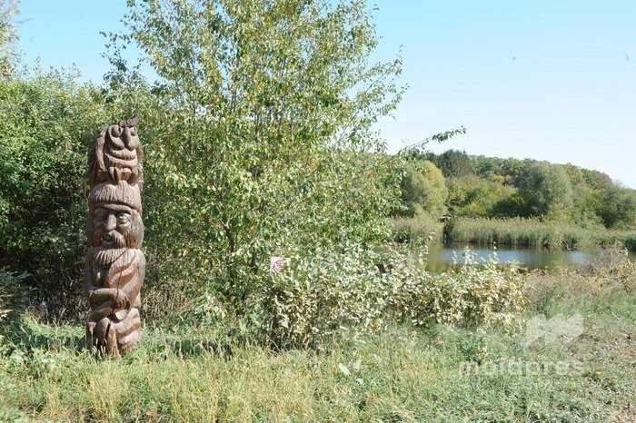 Деревянный резной идол в традиционном стиле на опушке заповедника «Plaiul Fagului» — у лесного пруда в регионе Кодры, Молдова