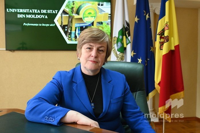 Ректор Молдавского государственного университета Отилия Дандара в своём рабочем кабинете на фоне флагов Молдовы и Евросоюза и баннера USM