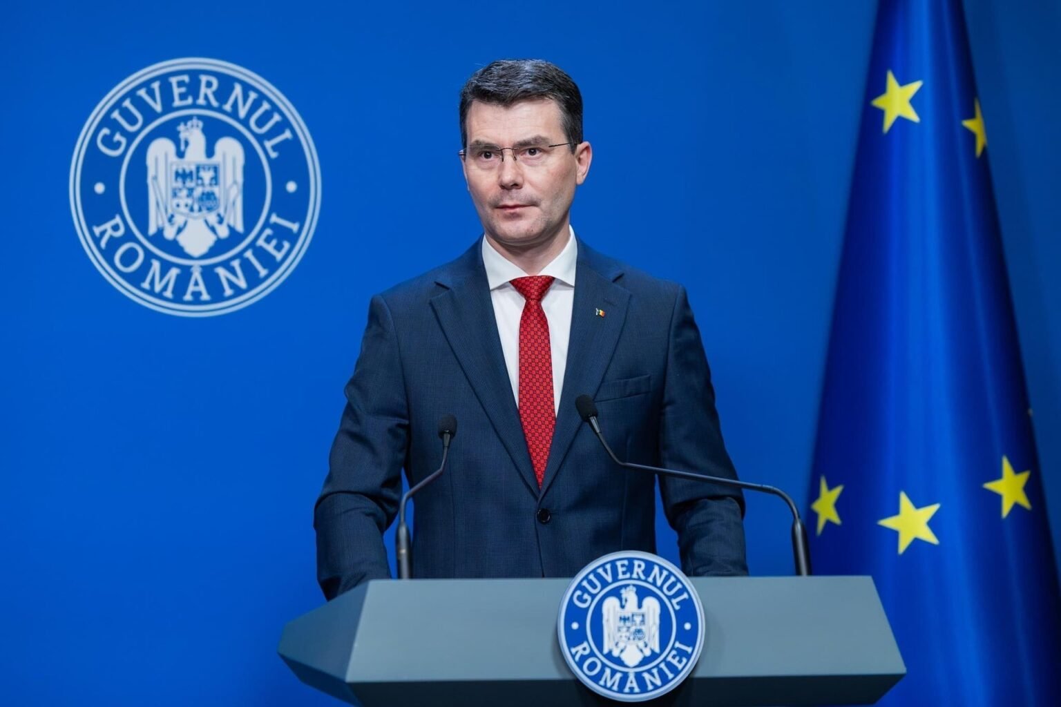 Хорациу Молдован, президент Национальной кассы медицинского страхования Румынии (CNAS), выступает за трибуной Правительства Румынии на фоне эмблемы «Guvernul României» и флага Евросоюза — брифинг, посвящённый запуску платформы рейтинга больниц