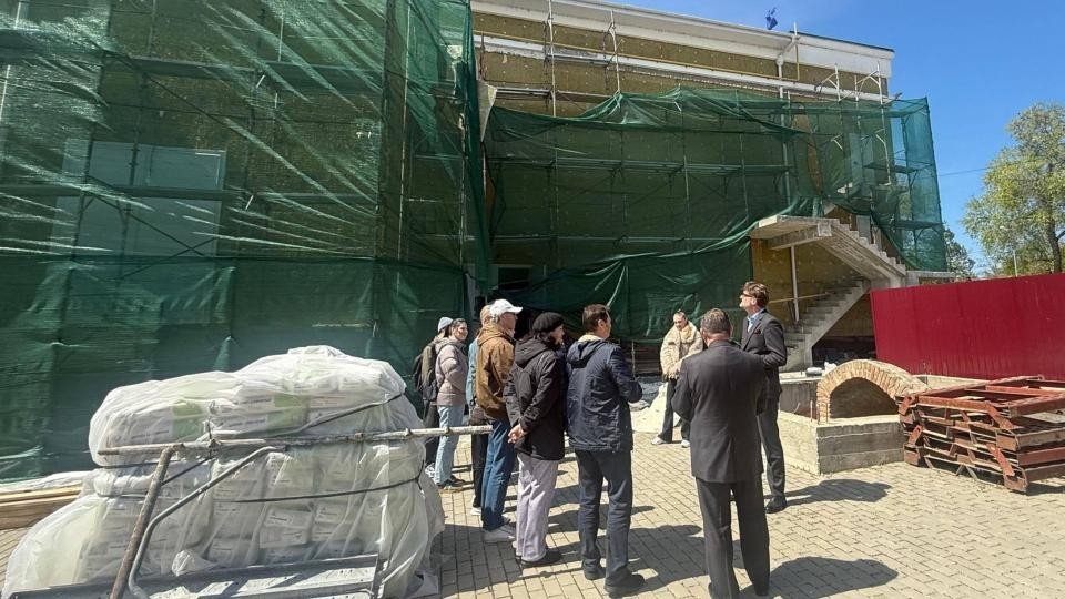 Строительная площадка нового здания Республиканского музыкально-драматического театра им. Б. П. Хашдеу в Кагуле: леса укрыты зелёной сеткой, посол Румынии Кристиан-Леон Цуркану общается с коллективом театра и представителями строительной компании во время визита 23 апреля 2026 года