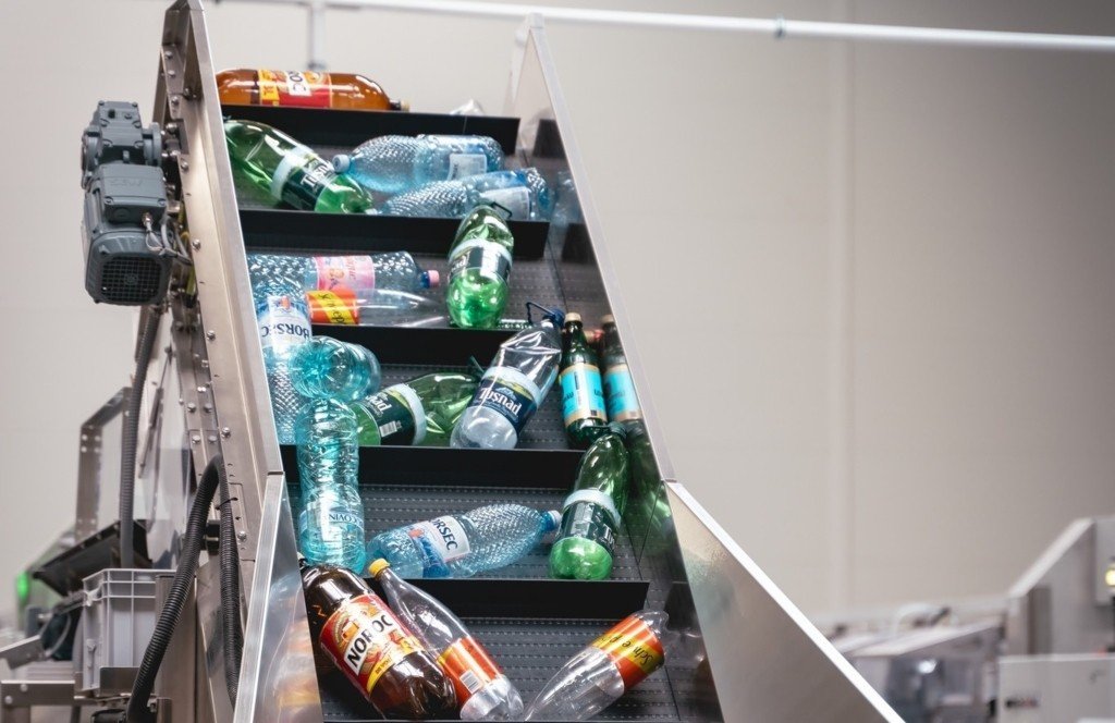 Пластиковые и стеклянные бутылки на конвейерной ленте сортировочного центра системы гарантии-возврата SGR