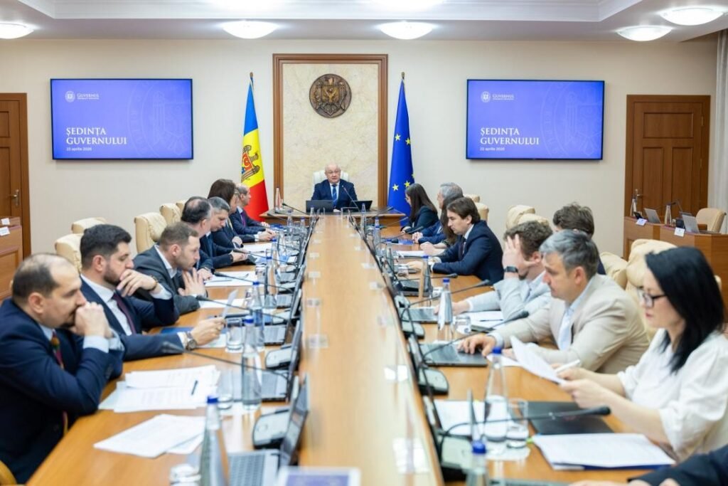 Зал заседаний правительства Молдовы: премьер-министр во главе стола, министры с документами, на экранах надпись «Ședința Guvernului»