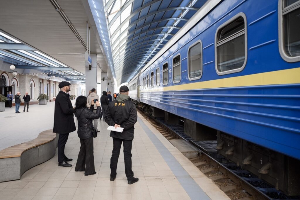 Пассажиры и сотрудник CFM в форме на обновлённой крытой платформе у пассажирского поезда Киев — Кишинёв сообщения с Украиной