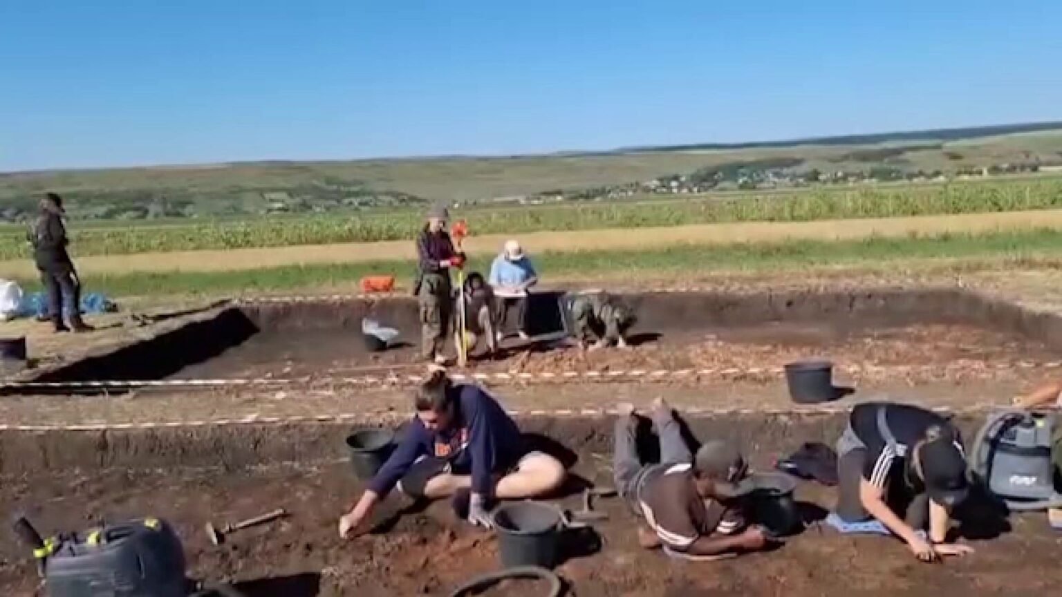 Археологи работают в раскопе мегаструктуры культуры Кукутень в Стэучень-Холм (уезд Ботошани, Румыния): на переднем плане участники экспедиции расчищают глинобитный пол постройки возрастом около 6000 лет