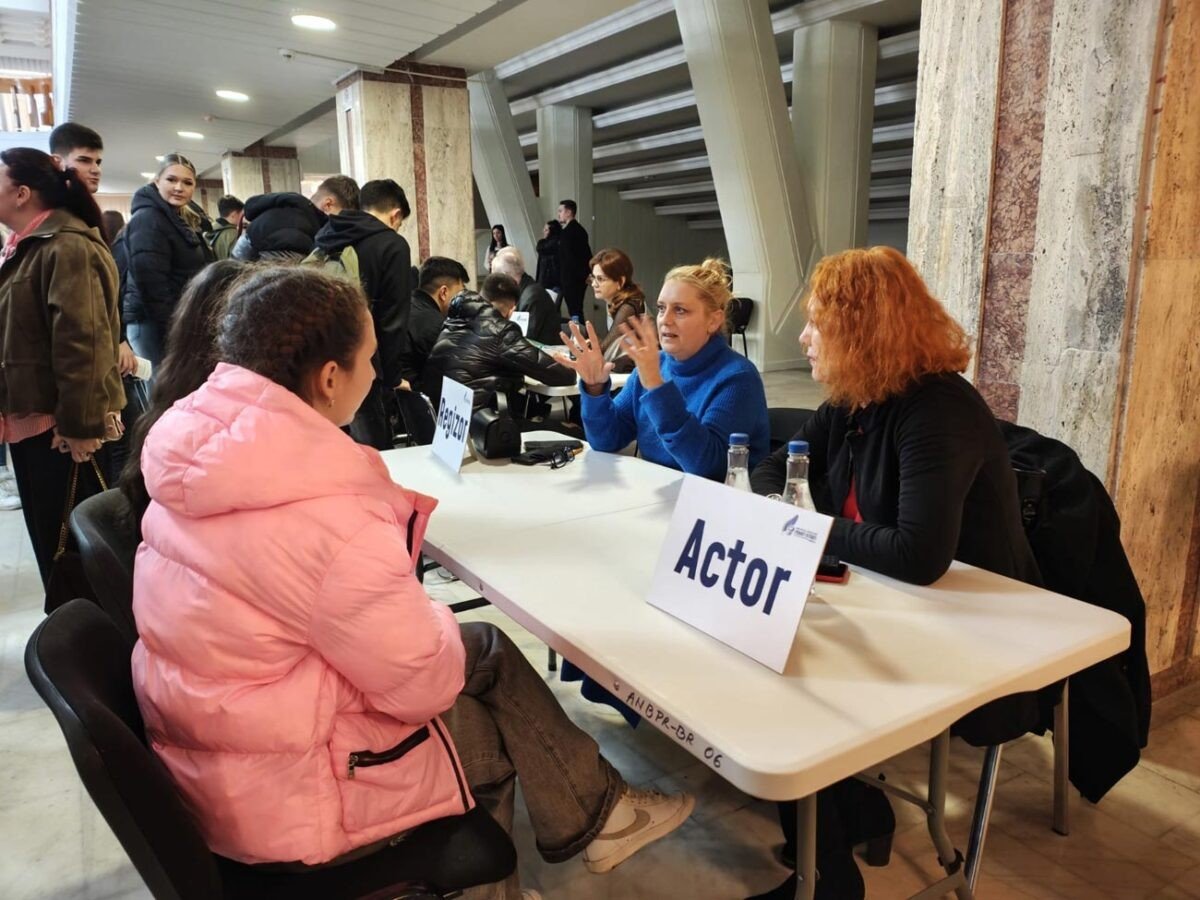 Ученица беседует со специалистами за столом с табличкой «Актёр» на мероприятии по профориентации в Брэиле