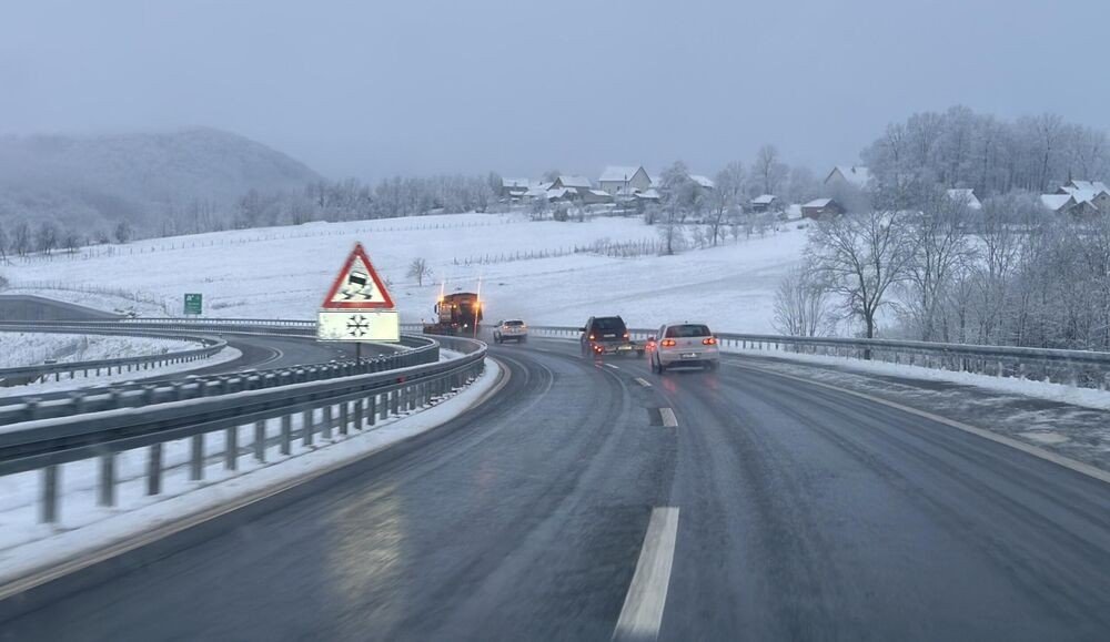 Заснеженная автомагистраль у Чачака — автомобили движутся по расчищенной дороге мимо предупреждающего знака