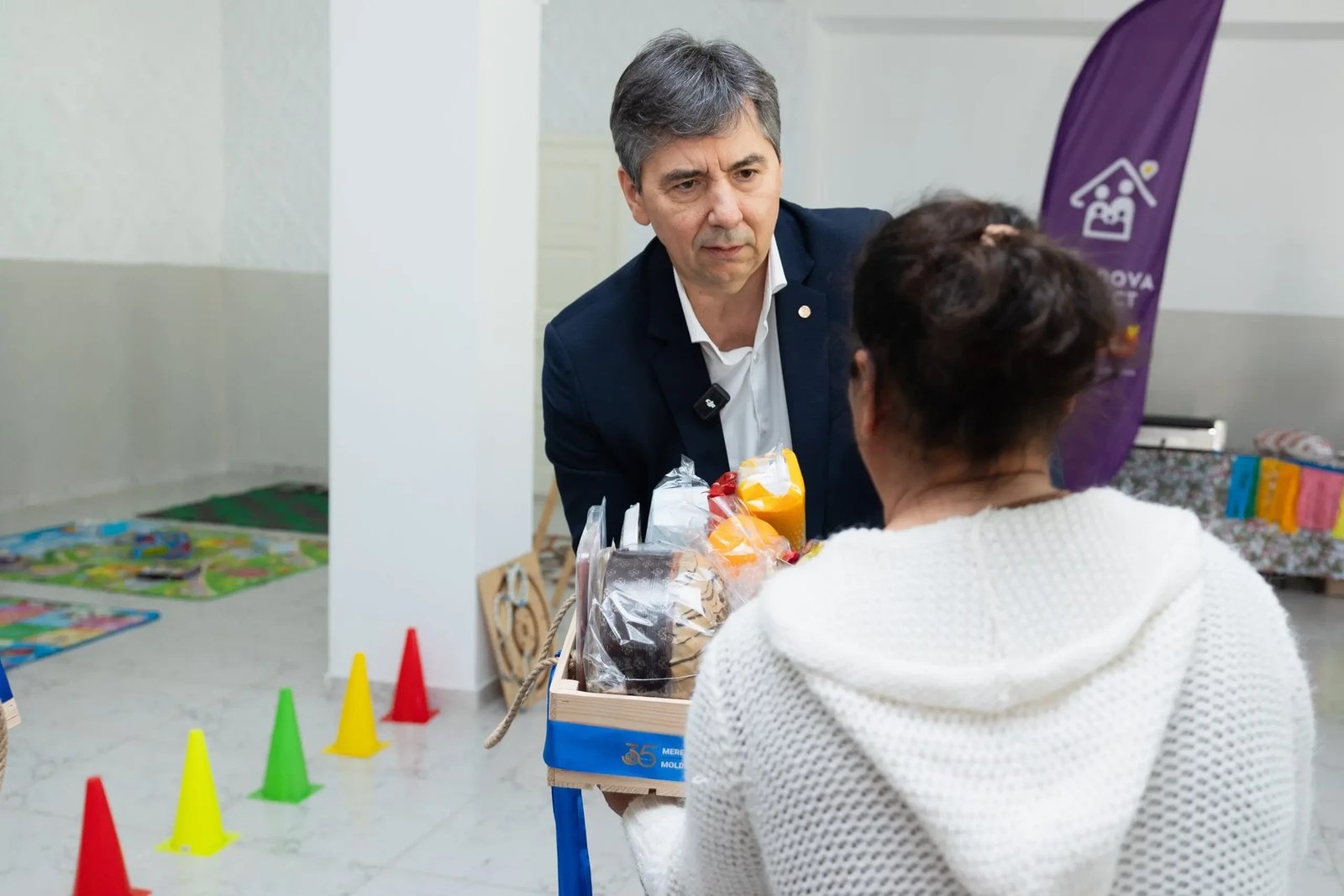 Представитель Moldindconbank вручает пасхальную корзину с продуктами участнице благотворительной акции