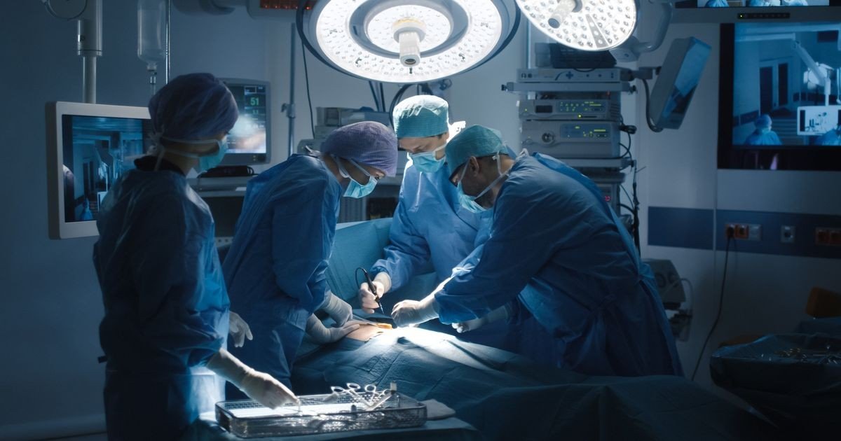 Бригада хирургов проводит операцию в современной операционной, оснащённой мониторами и хирургическими лампами