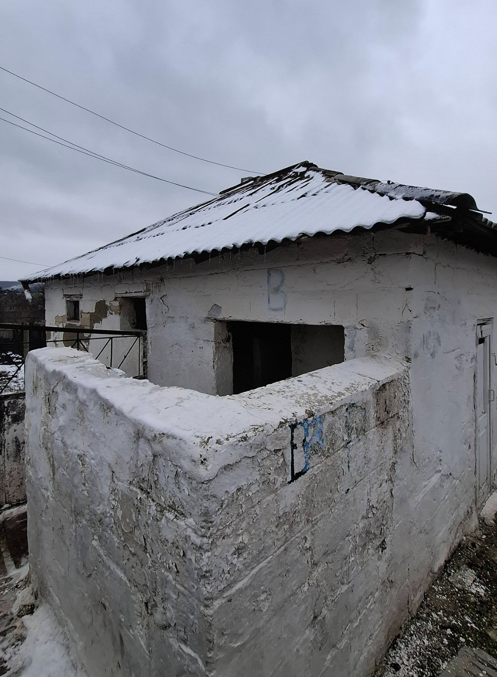 Наружный вид санитарного блока гимназии имени короля Михая I в Чимишене — обветшалое здание с повреждённой крышей и осыпавшейся штукатуркой