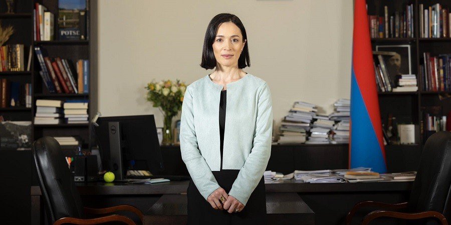 Министр ОНКС Армении Жанна Андреасян в рабочем кабинете, за спиной — книжные полки и государственный флаг