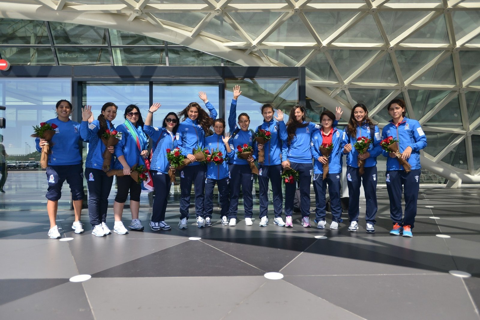 Игроки женской сборной Азербайджана по футболу с букетами цветов позируют в аэропорту после возвращения с международного матча