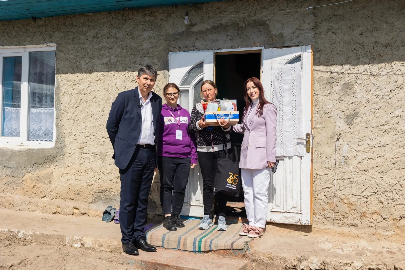 Участники благотворительной акции у дома сельской семьи в Хынчештском районе Молдовы