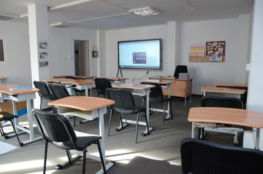 Современный учебный класс частной школы с интерактивной доской и индивидуальными партами