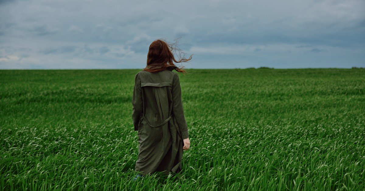 Девушка идёт по зелёному полю под грозовым небом — тёплая, но переменчивая весна на равнинах Румынии