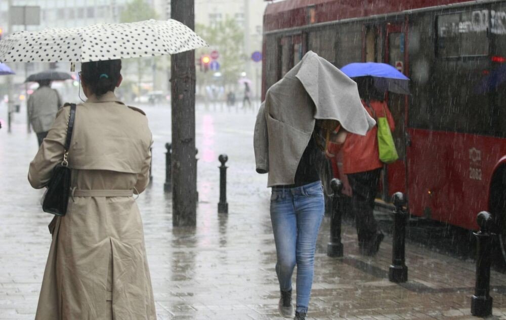 Прохожие под зонтами на городской улице во время сильного ливня