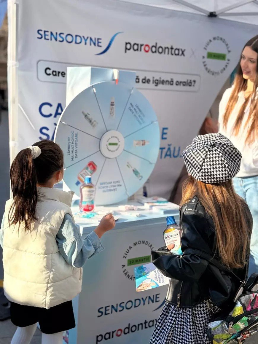 Две девочки изучают интерактивное колесо с правилами ухода за полостью рта на стенде Sensodyne и Parodontax во время Каравана здоровья полости рта
