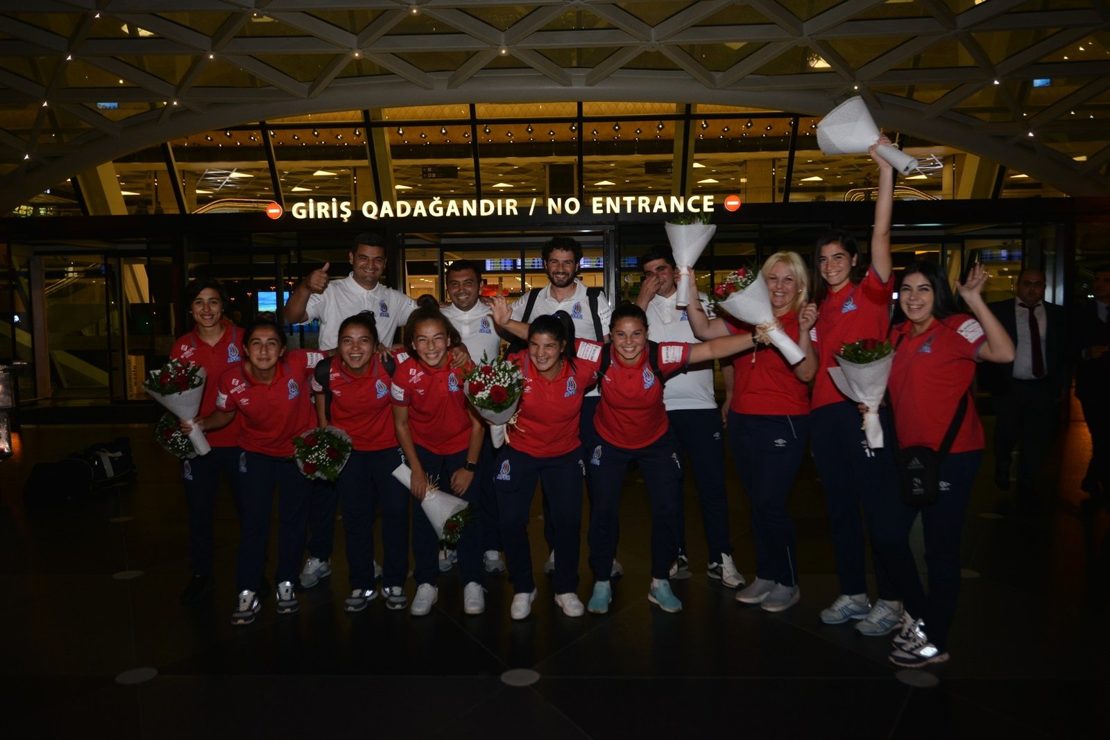 Футболистки и тренерский штаб девичьей сборной Азербайджана U-19 с букетами цветов у входа в аэропорт