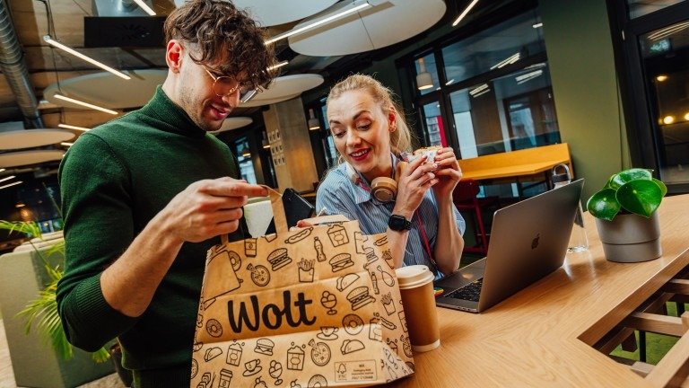 Клиенты распаковывают заказ из фирменного пакета Wolt в коворкинг-пространстве