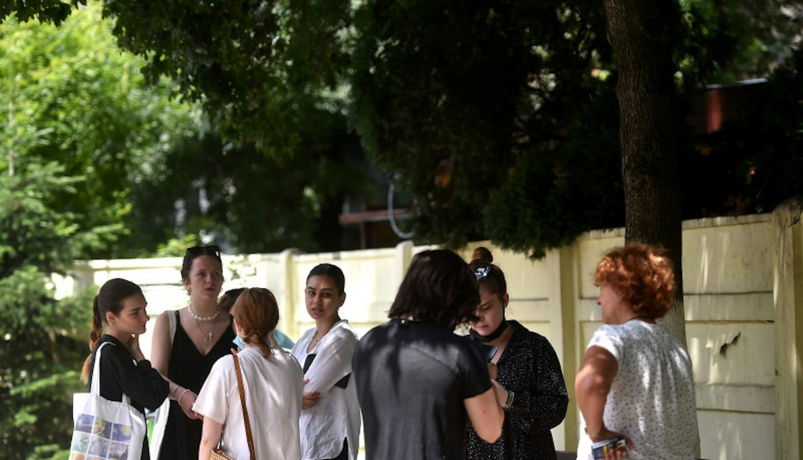 Группа людей у входа в экзаменационный центр обсуждает результаты пробного бакалавриата