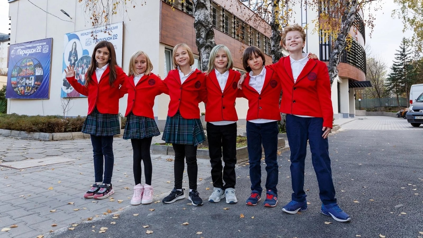 Школьники в красных форменных жакетах перед зданием учебного заведения