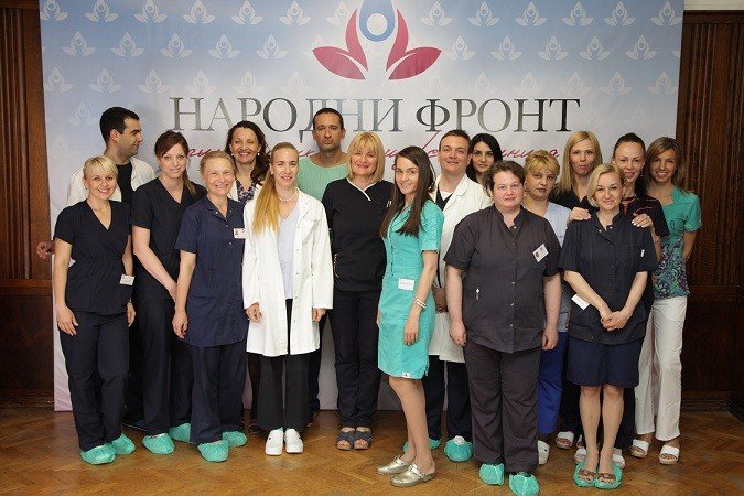 Коллектив акушерско-гинекологической клиники «Народни фронт» (Белград) в составе врачей и акушерок перед логотипом учреждения