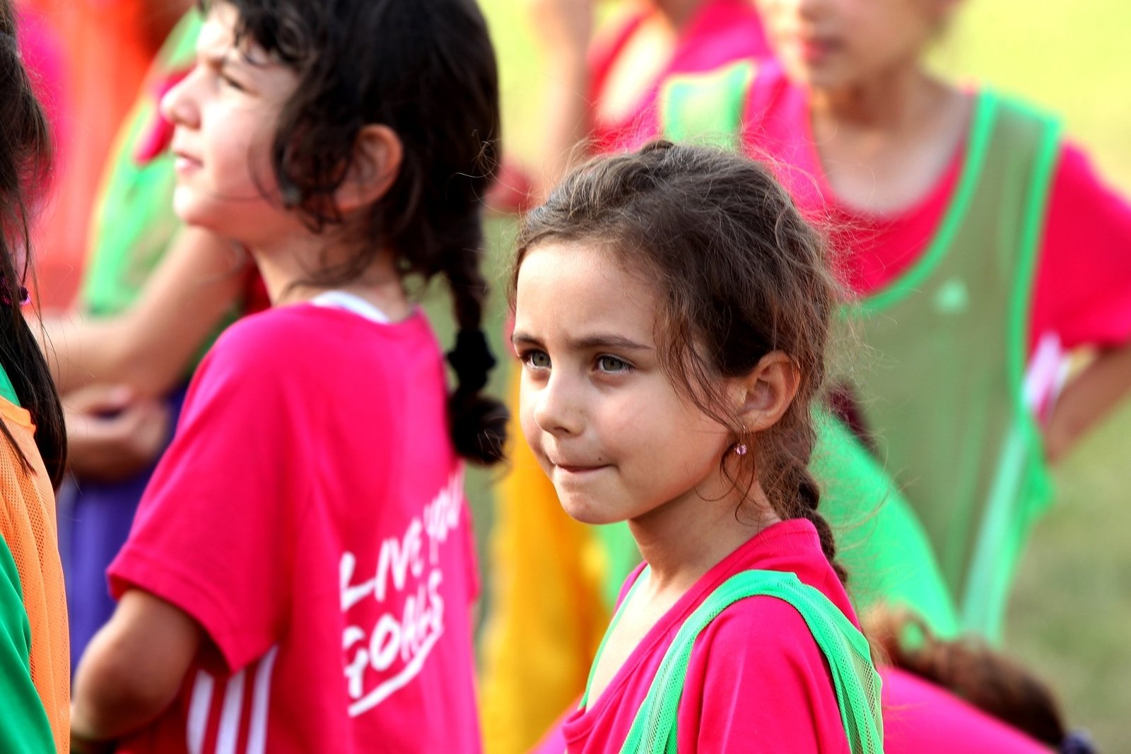 Юные участницы программы AFFA по развитию женского футбола Live Your Goals в розовых футболках и зелёных манишках на тренировке