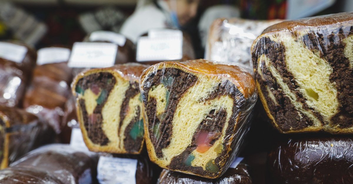 Упакованные в плёнку домашние куличи с разноцветной начинкой выложены на продажу на рыночном прилавке