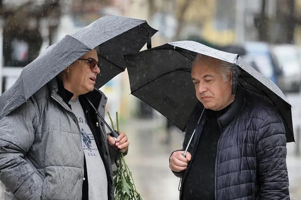 Скорбящие под зонтами несут цветы к храму на прощание с Кирилом Амповым