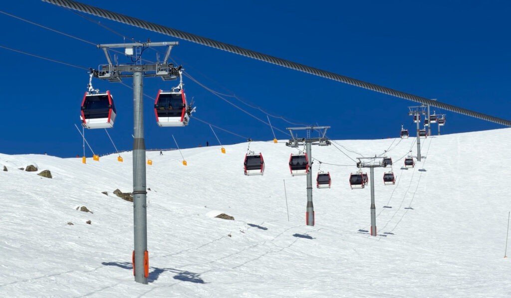 Современная гондольная канатная дорога на курорте Гудаури на фоне голубого неба и заснеженных склонов